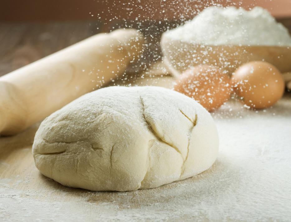 Kneaded dough, surrounded by eggs, wheat and roller