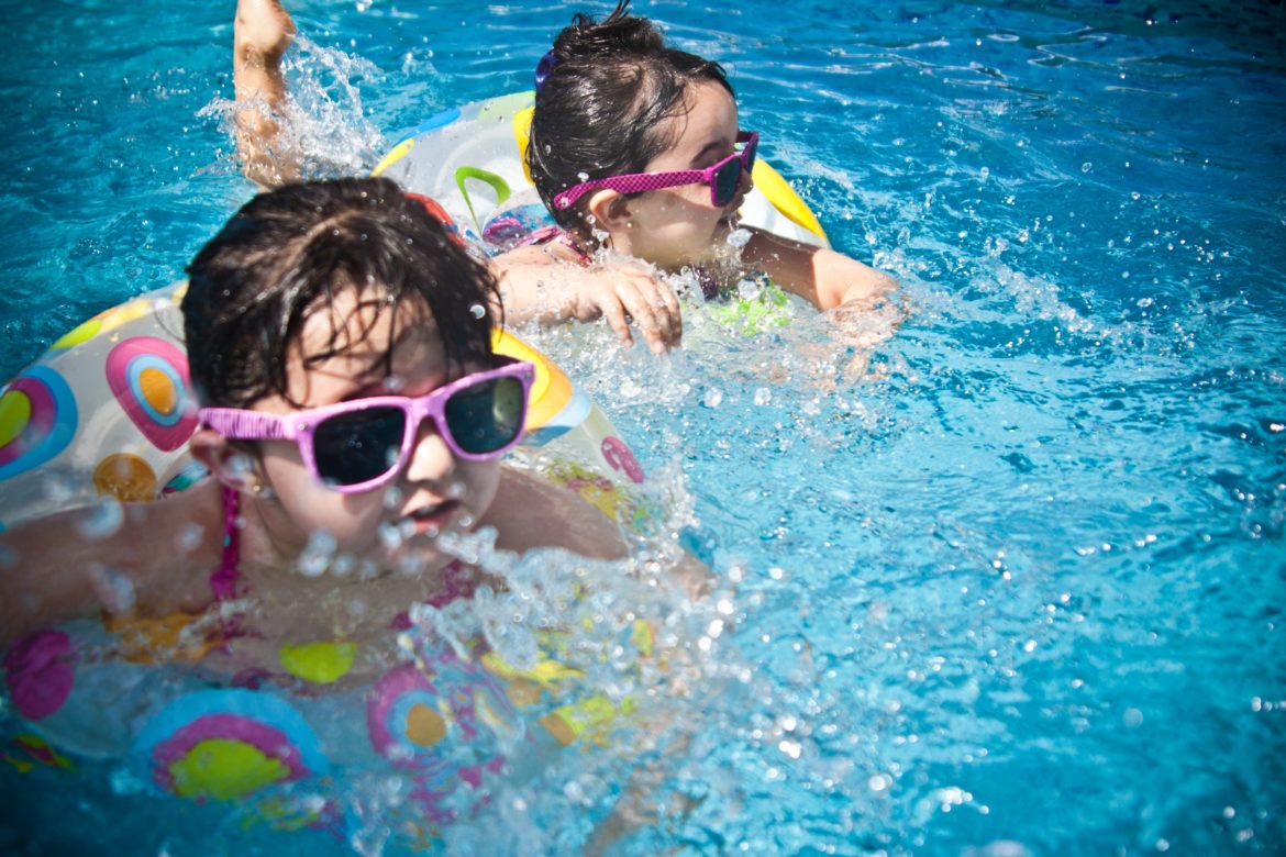 Two Kids Wearing Floats and Sunglasses while in the Pool
